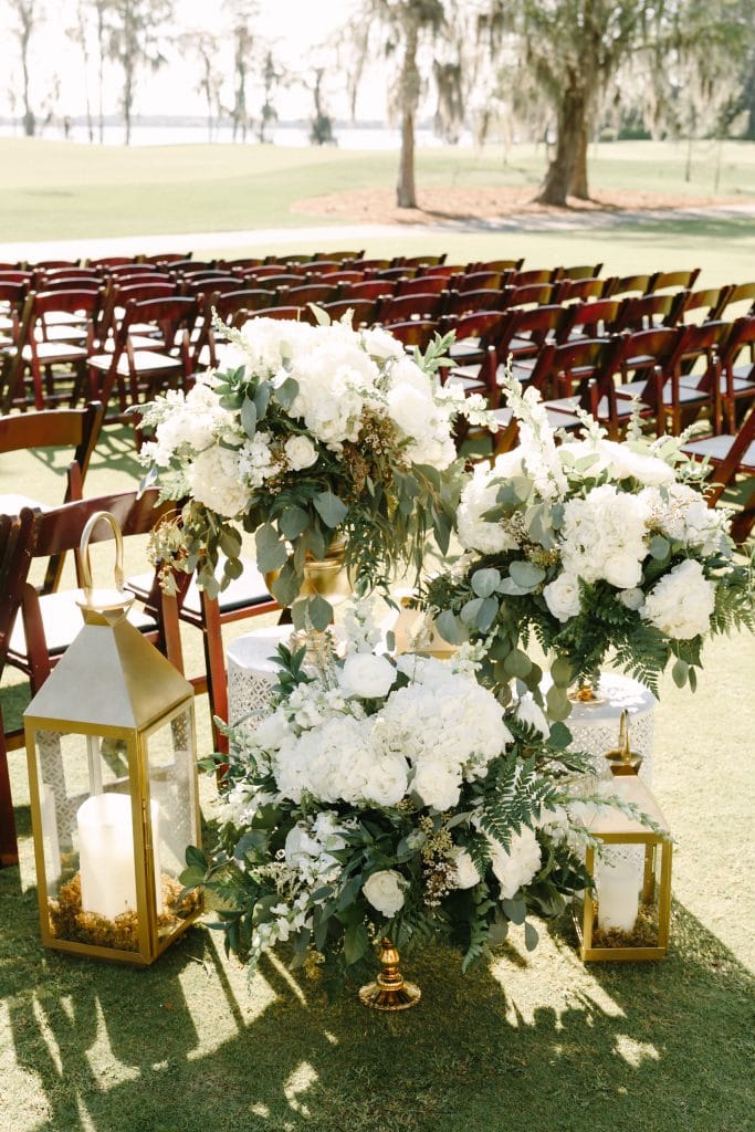 outdoor wedding ceremony aisle entrance with white candles and white floral arrangements by Runway Events