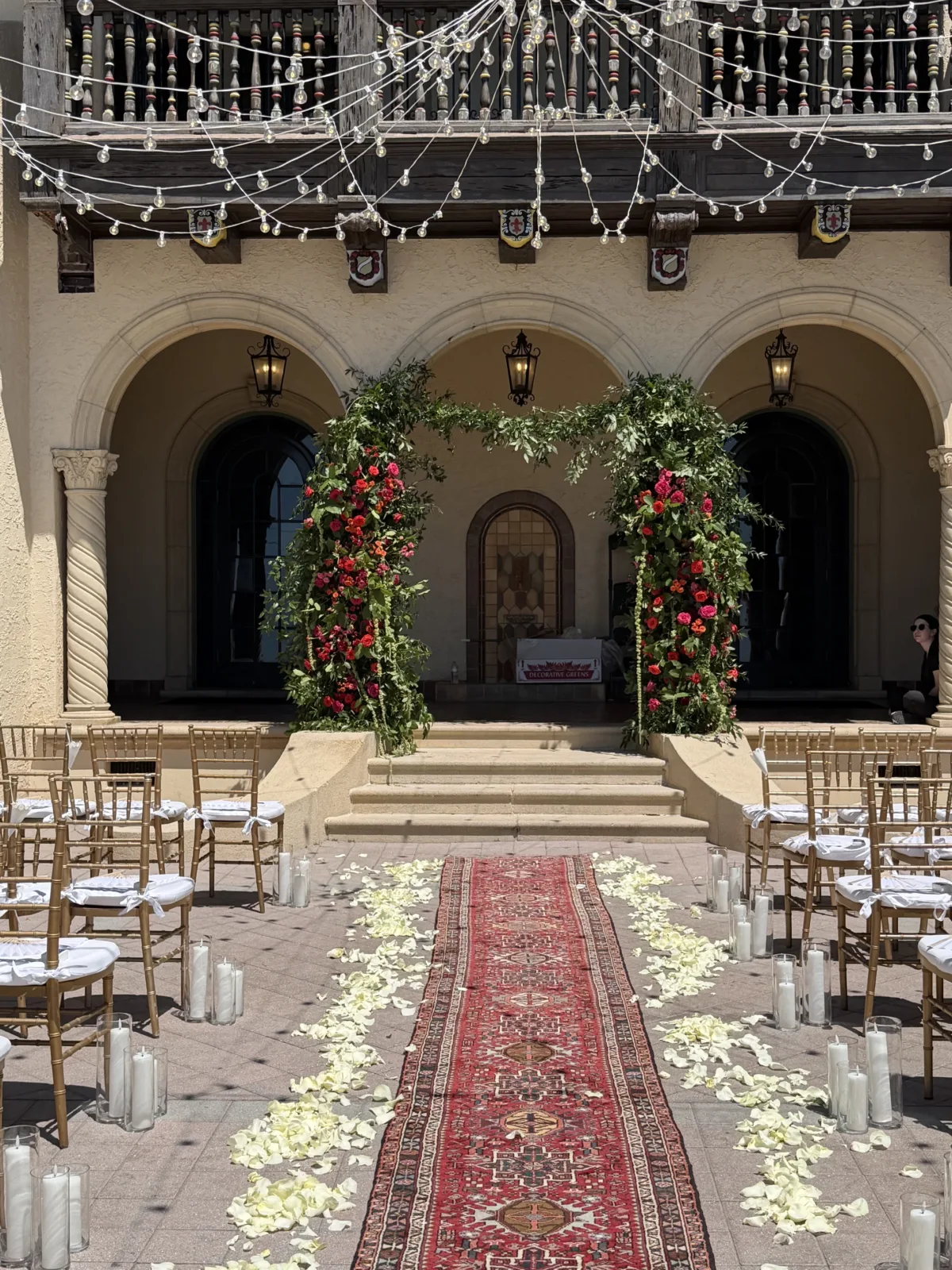 exterior wedding ceremony with floral arch and gold chairs