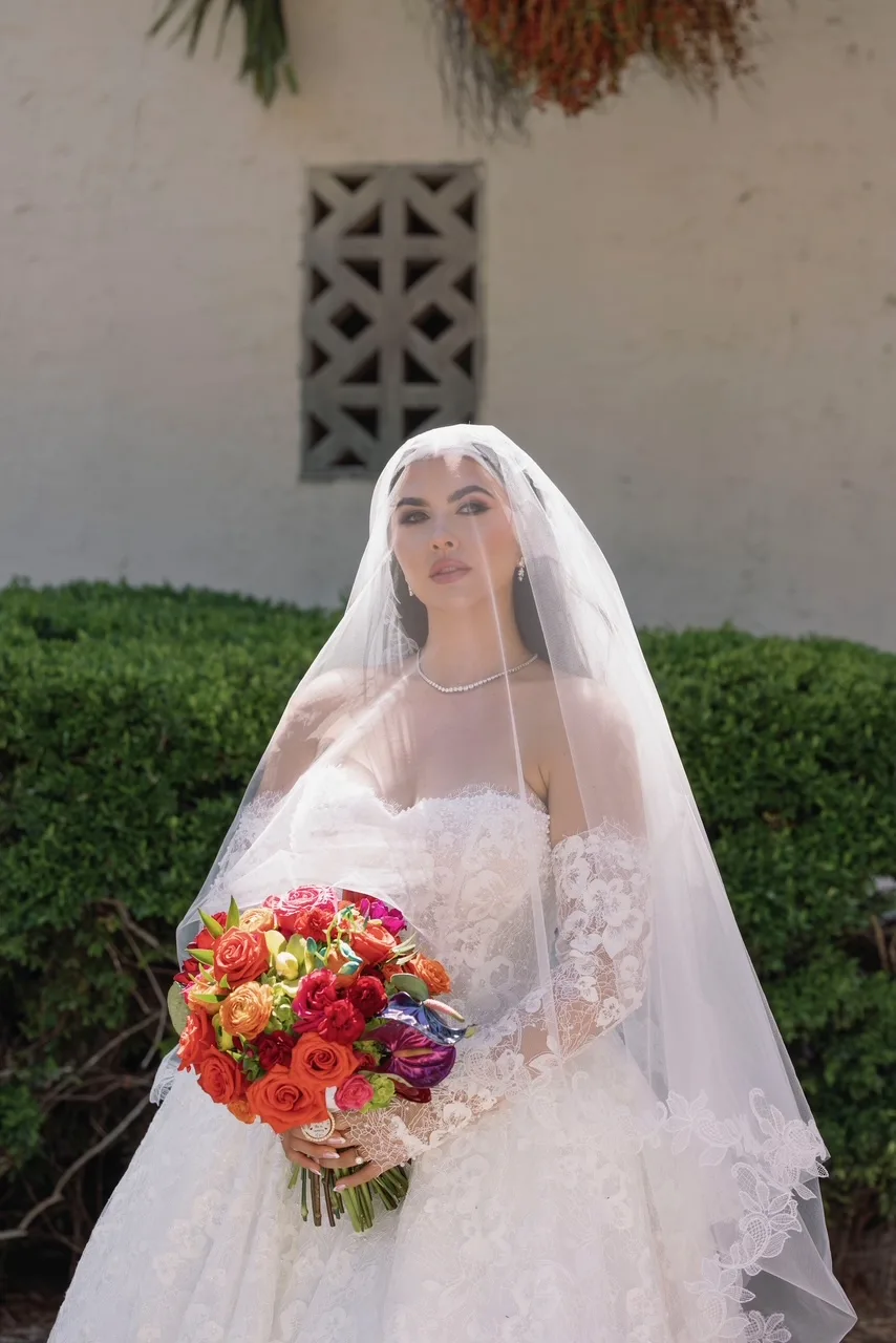bride with white veil holding red and pink floral bouquet for orlando wedding
