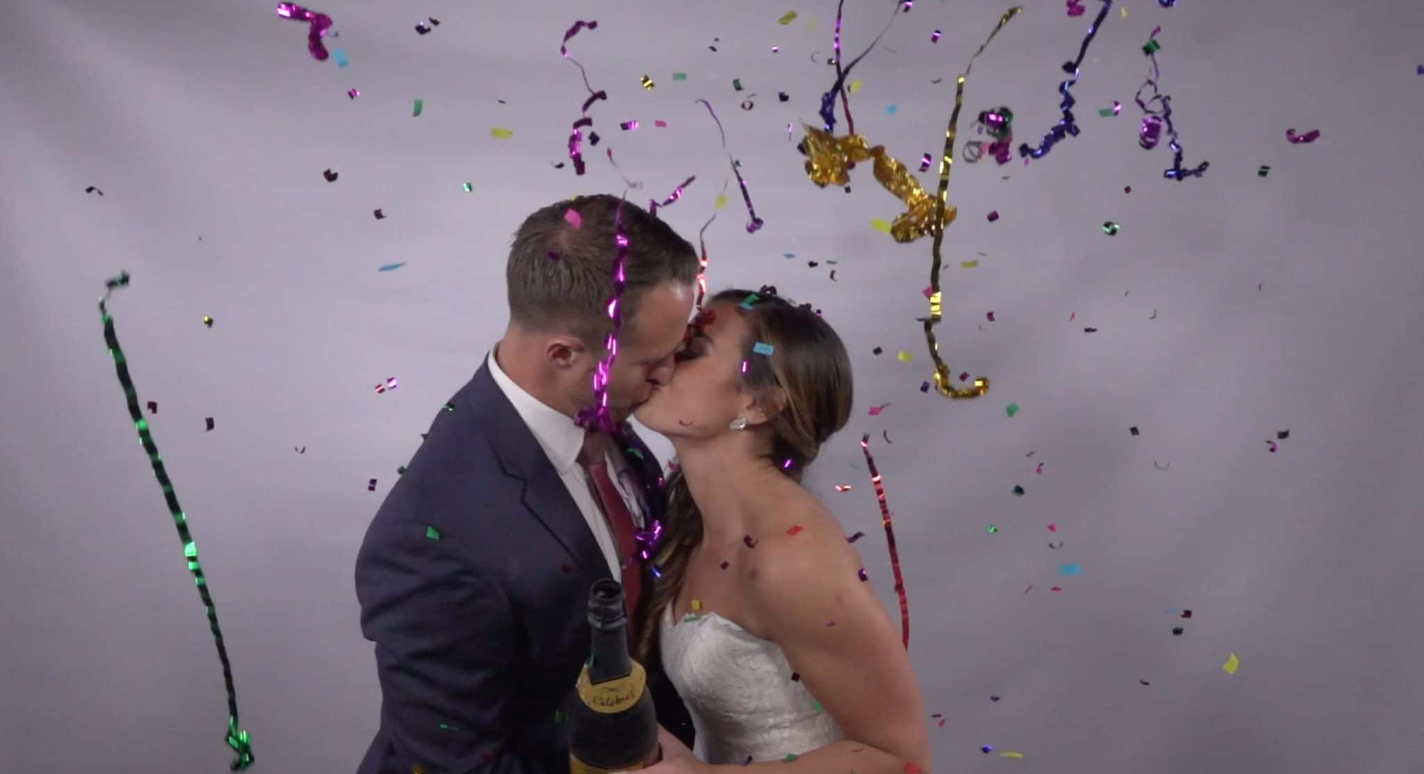 Omarvelous Productions - bride and groom kissing with confetti, streamers, and champagne bottle
