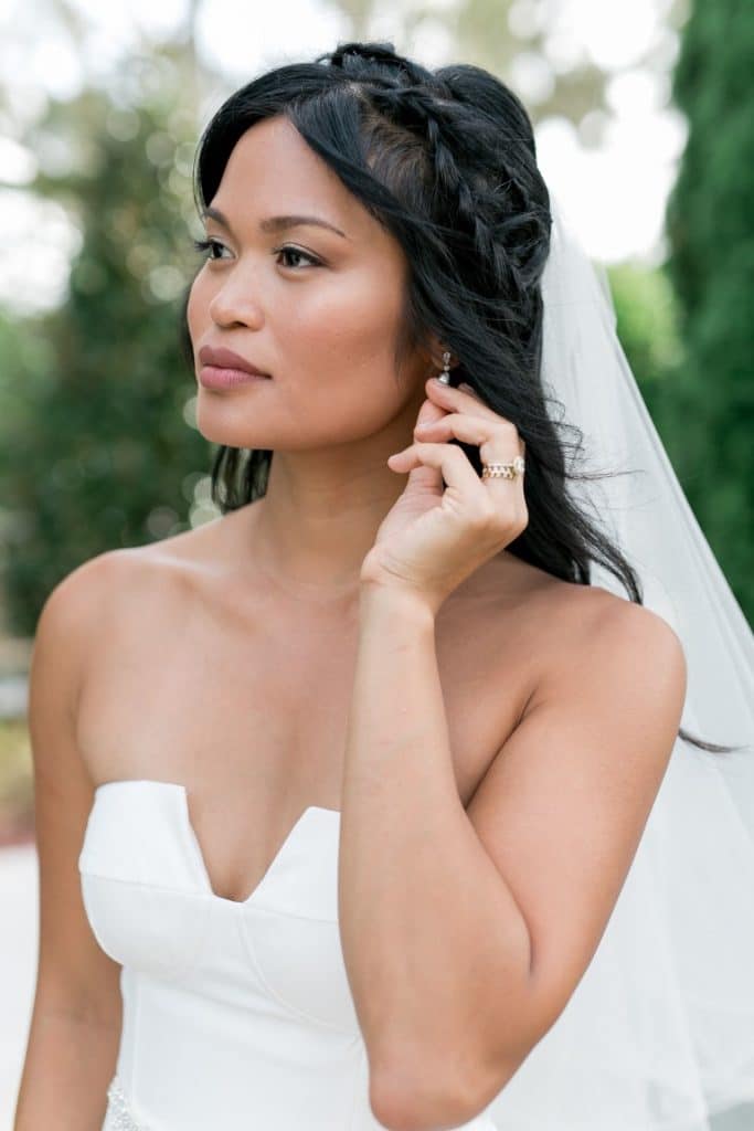 bride holding her earring in a strapless wedding gown