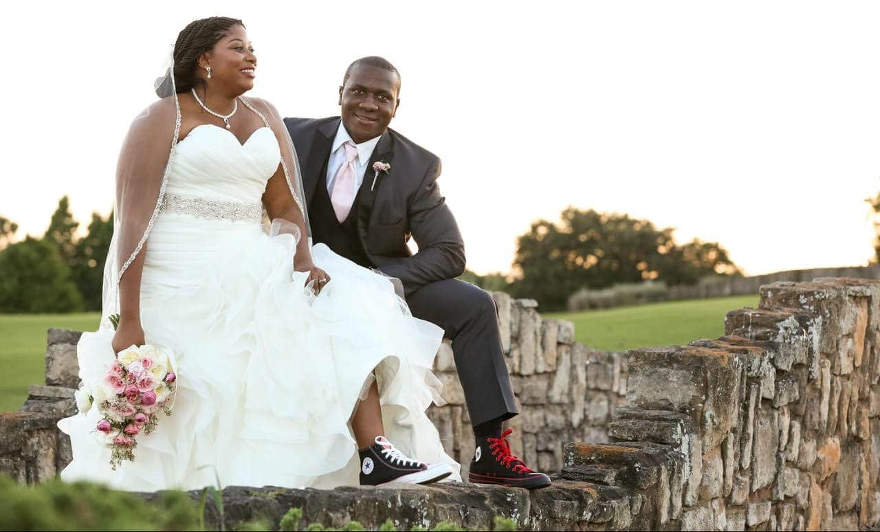 Live Happy Studio - bride & groom sitting on a rockwall showing off their converse sneakers