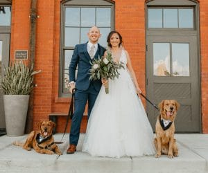Furry-Ventures-Pet-Care-bride and groom photo with dogs against orange building