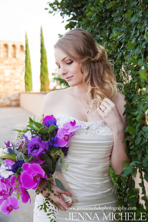 bride looking down at fuschia colored bouquet with flowing hair and make-up styled by Jazz It Up Artistry