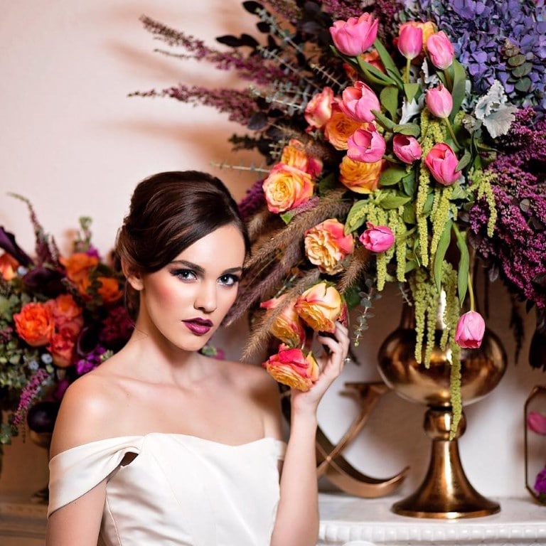 woman styled by Jazz It Up Artistry holding roses from tall centerpiece of roses and tulips