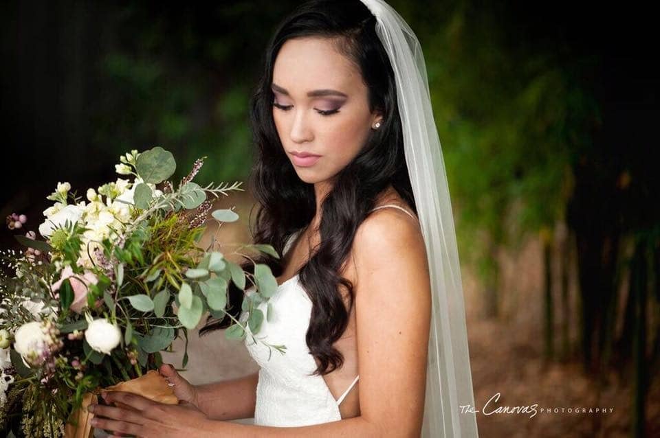 bride looking at her bouquet of white and greenery