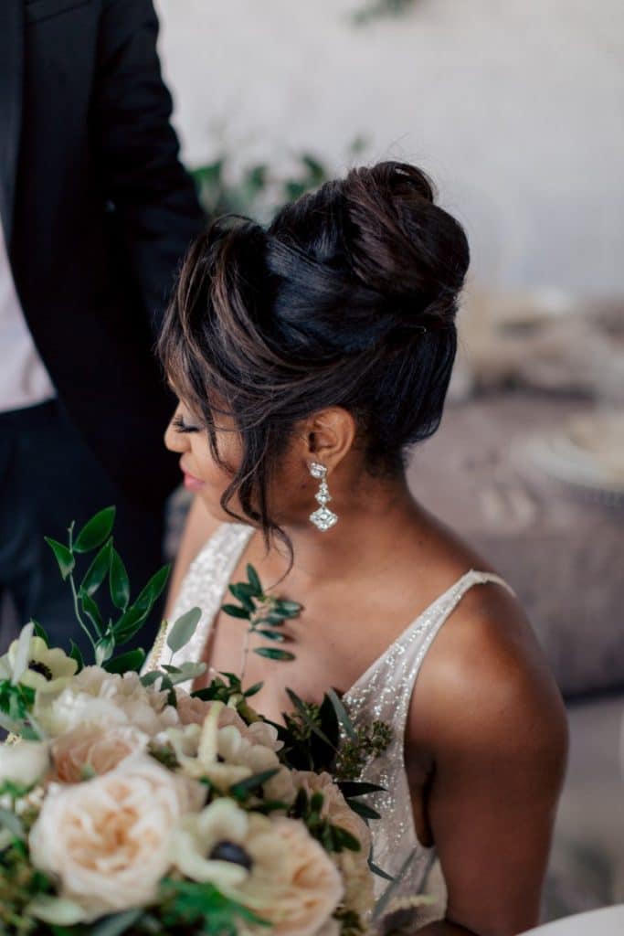 bride with drop earrings and champage floral bouquet and upswept hairdo done by Jazz It Up Artistry