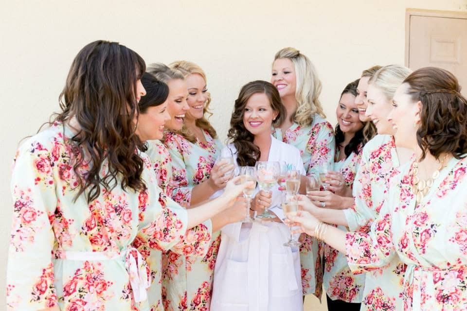 bride with wedding party in rose covered robes with styling by Jazz It Up Artistry