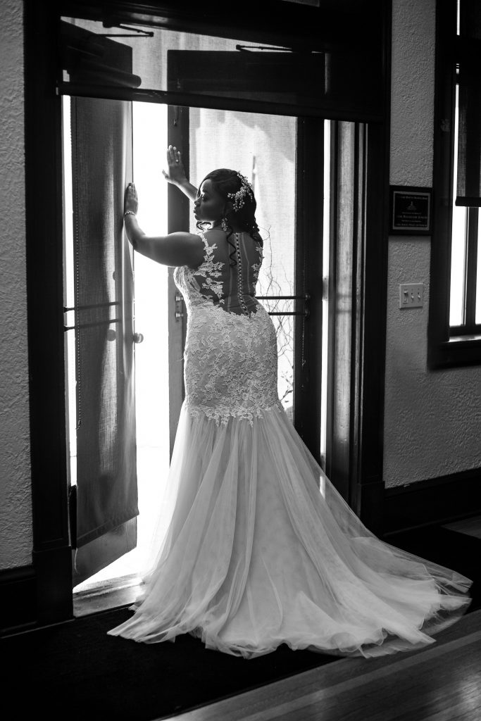 bride showing back of her dress standing in front of door
