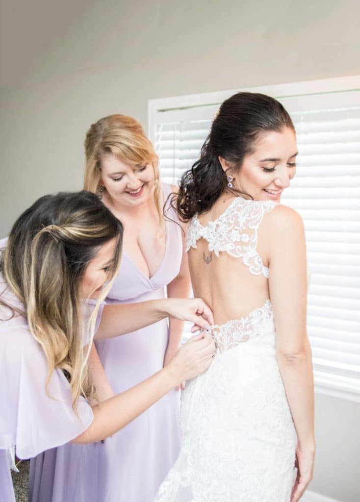 Honeywood Photography photo of bride getting help dressing from her bridesmaids in lavendar