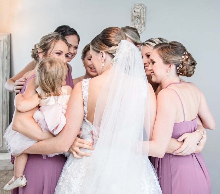Honeywood Photography photo of bridesmaids and bride having a group hug with a toddler.