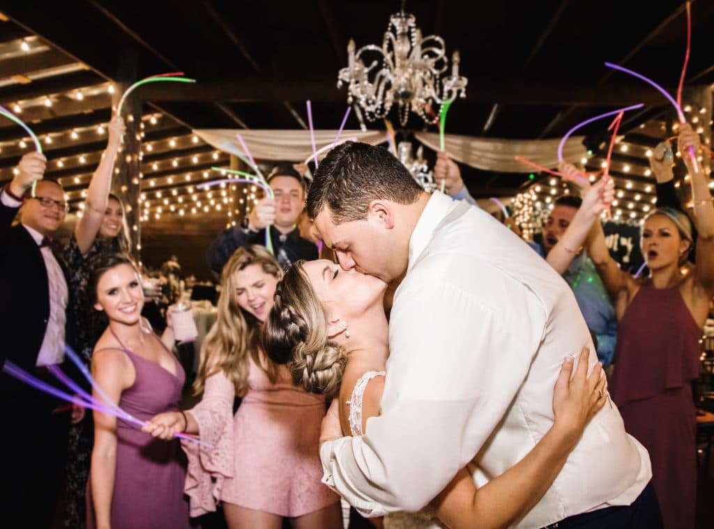 Honeywood Photography photo of groom kissing his bride under lights and sparklers.