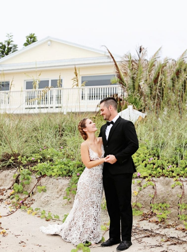 Honeywood Photography photo of bride and groom at the beach with a yellow seaside cottage on the dune