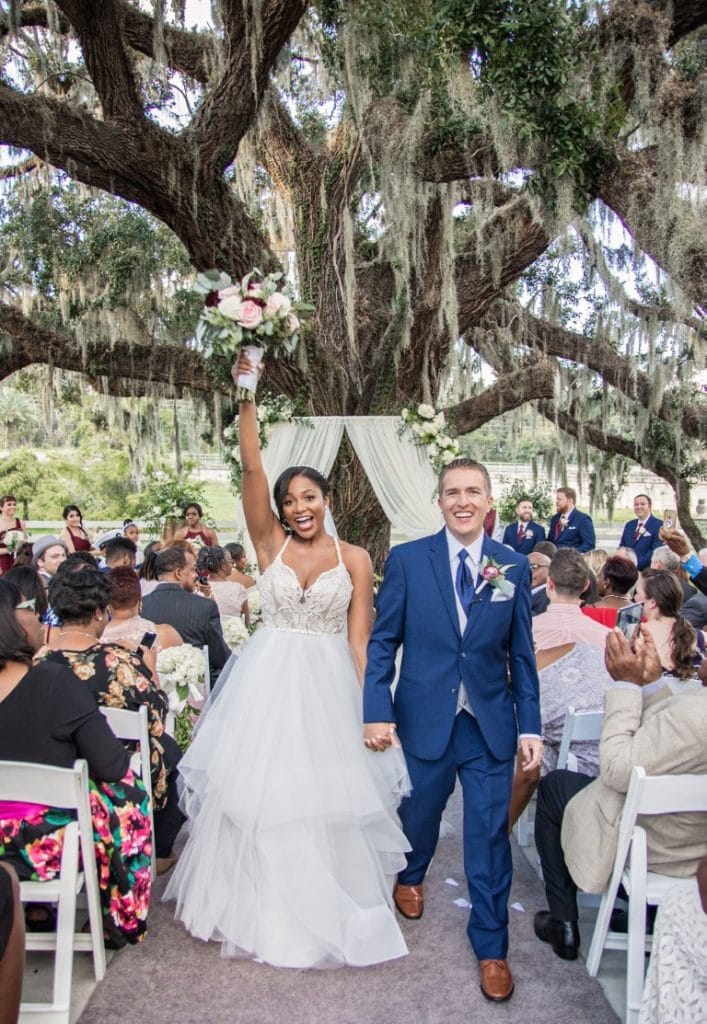 Honeywood Photography photo of bride and groom walking down the aisle at their outdoor ceremony under a large oak tree draped in Spanish moss