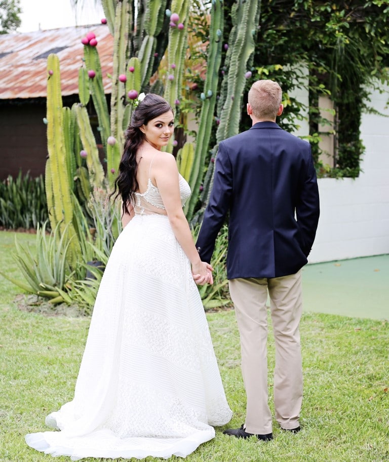 Honeywood Photography photo of bride looking over her shoulder walking in a cactus garden with her groom