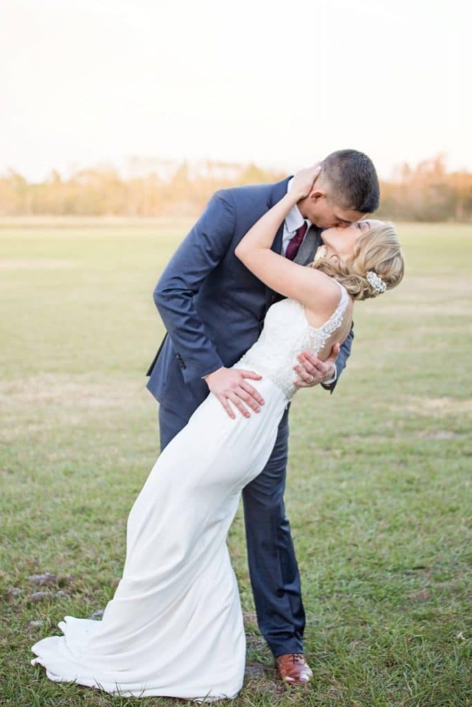 Honeywood Photography photo of a groom dipping his bride for a kiss in an outdoor field