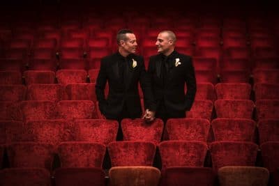 two grooms looking at each other, inside a theater, red velvet chairs, Orlando, FL