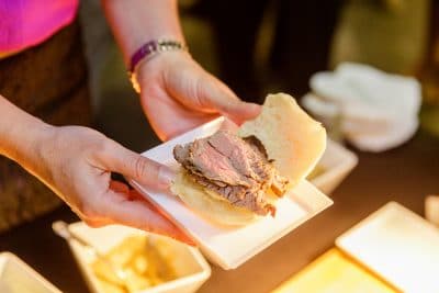 close up of person from Foodie Catering making a sandwich at a wedding reception