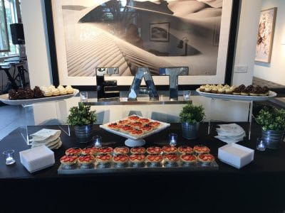 table set up at a wedding reception filled with bite sized food and a large Eat sign by Foodie Catering