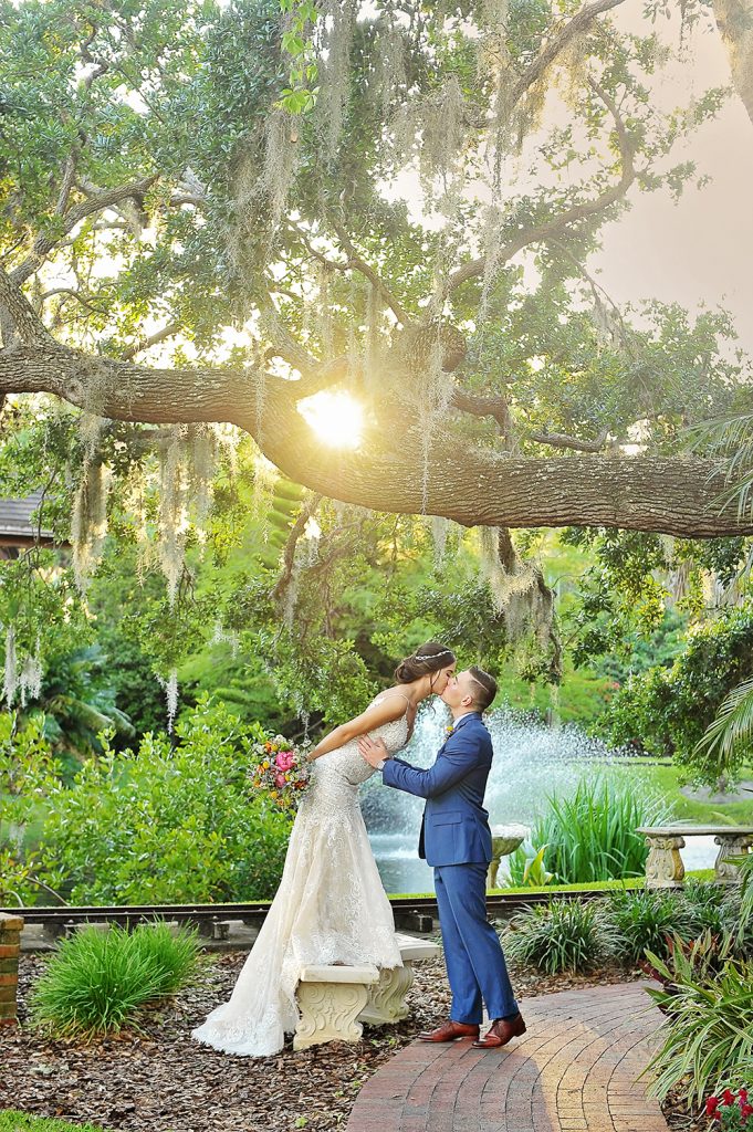 Jennifer Juniper Photography - Bride and groom kissing in a garden at sunset