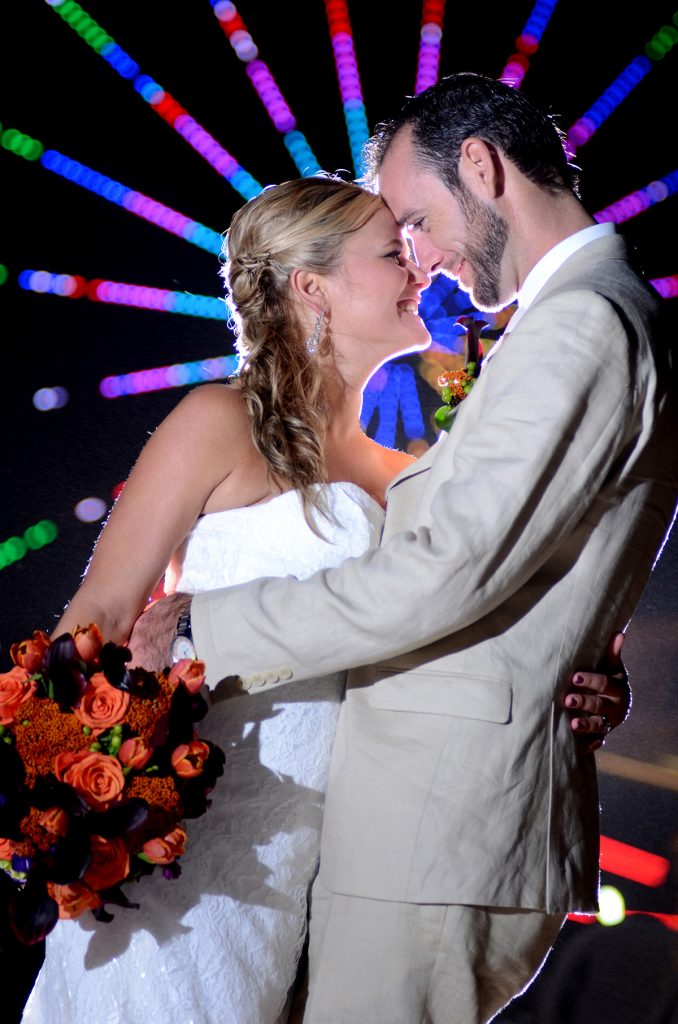 Jennifer Juniper Photography - Bride and groom kissing at night with lighted ferris wheel in background