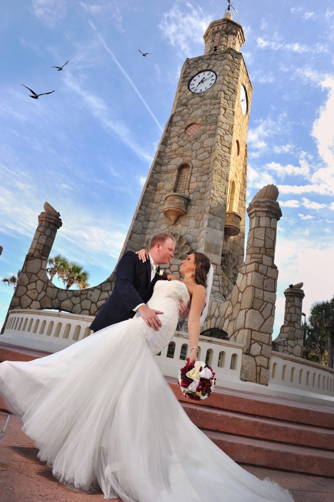 Jennifer Juniper Photography - Groom holding bride in front of clock tower at beach