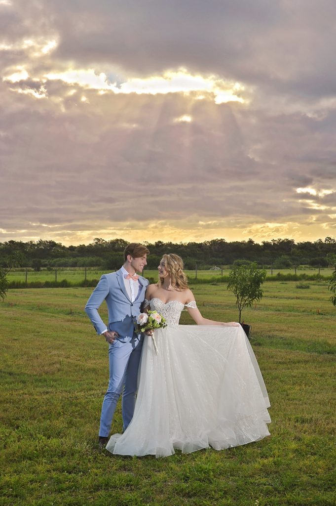 Jennifer Juniper Photography - Bride and groom standing in field at sunset