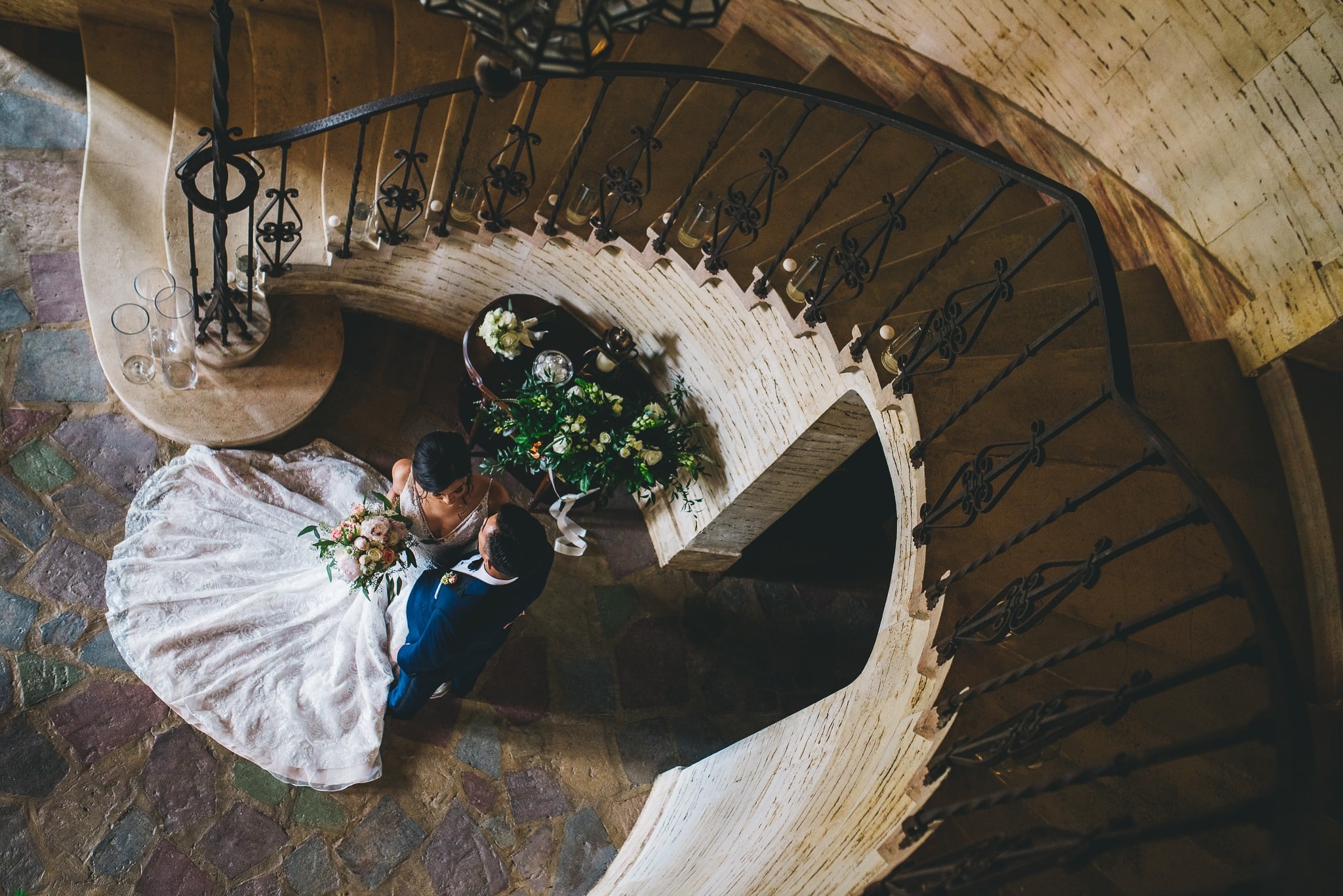 picture from above of bride & groom under spiral staircase