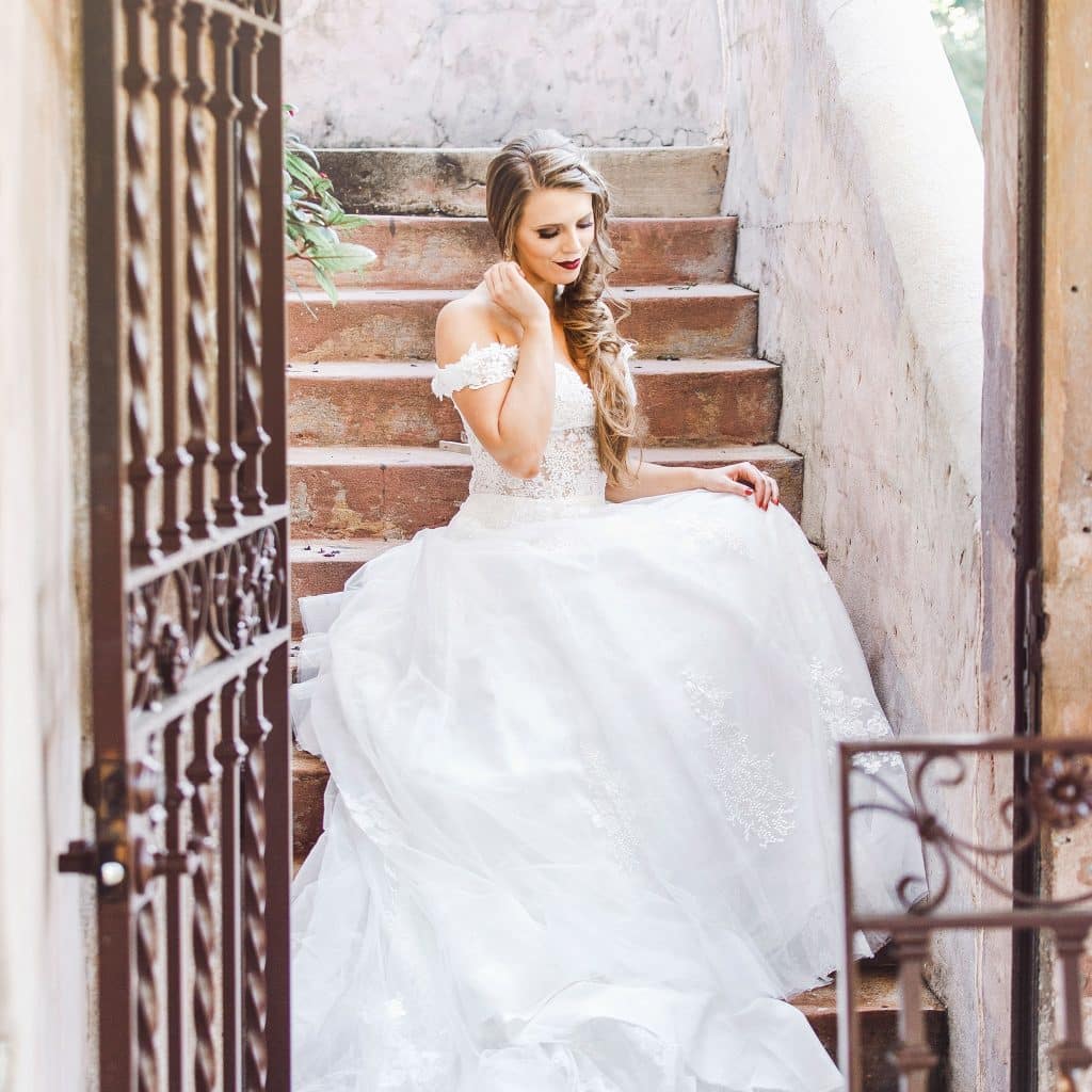 bride standing on the steps outside behind a metal gate