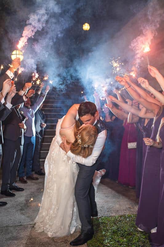 Complete Weddings + Events bride and groom kissing during sparkler exit