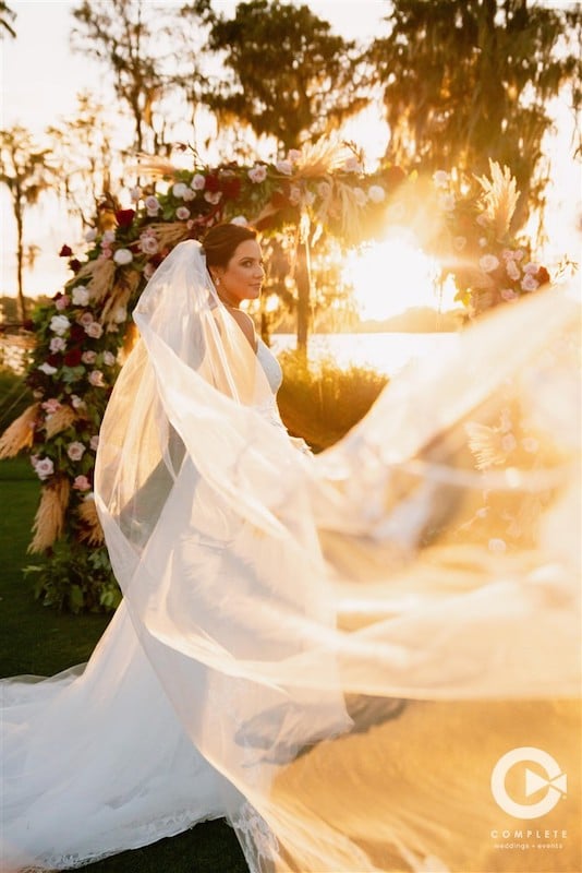 Complete Weddings + Events bride and her veil floating in breeze during sunset