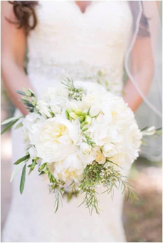 Lowe and Behold bride holding white flower bouquet in front of her dress