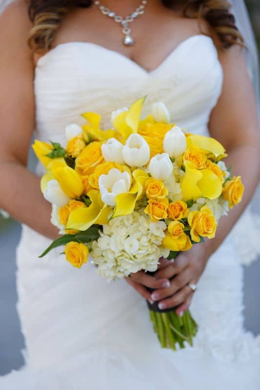 Lowe and Behold bride holding a bouquet featuring yellow flowers