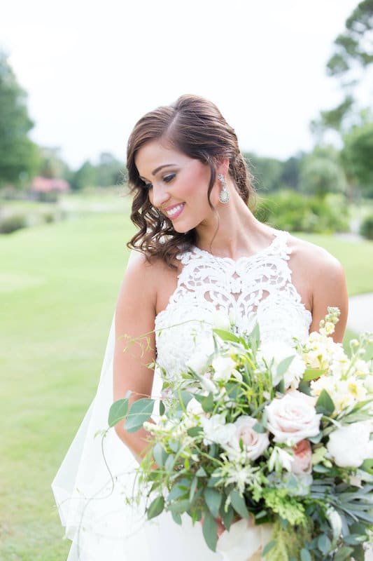 Lowe and Behold beautiful bride posing with flower bouquet while standing outside