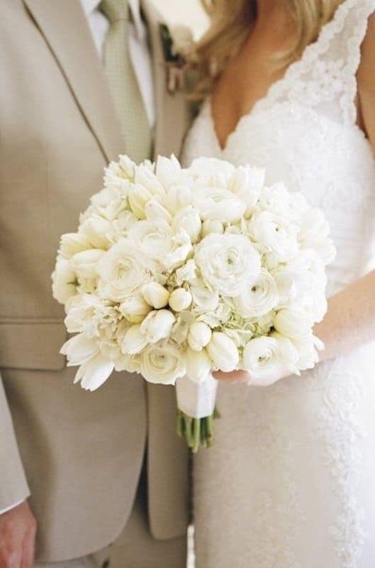 Lowe and Behold bride and groom posing with all white flower bouquet