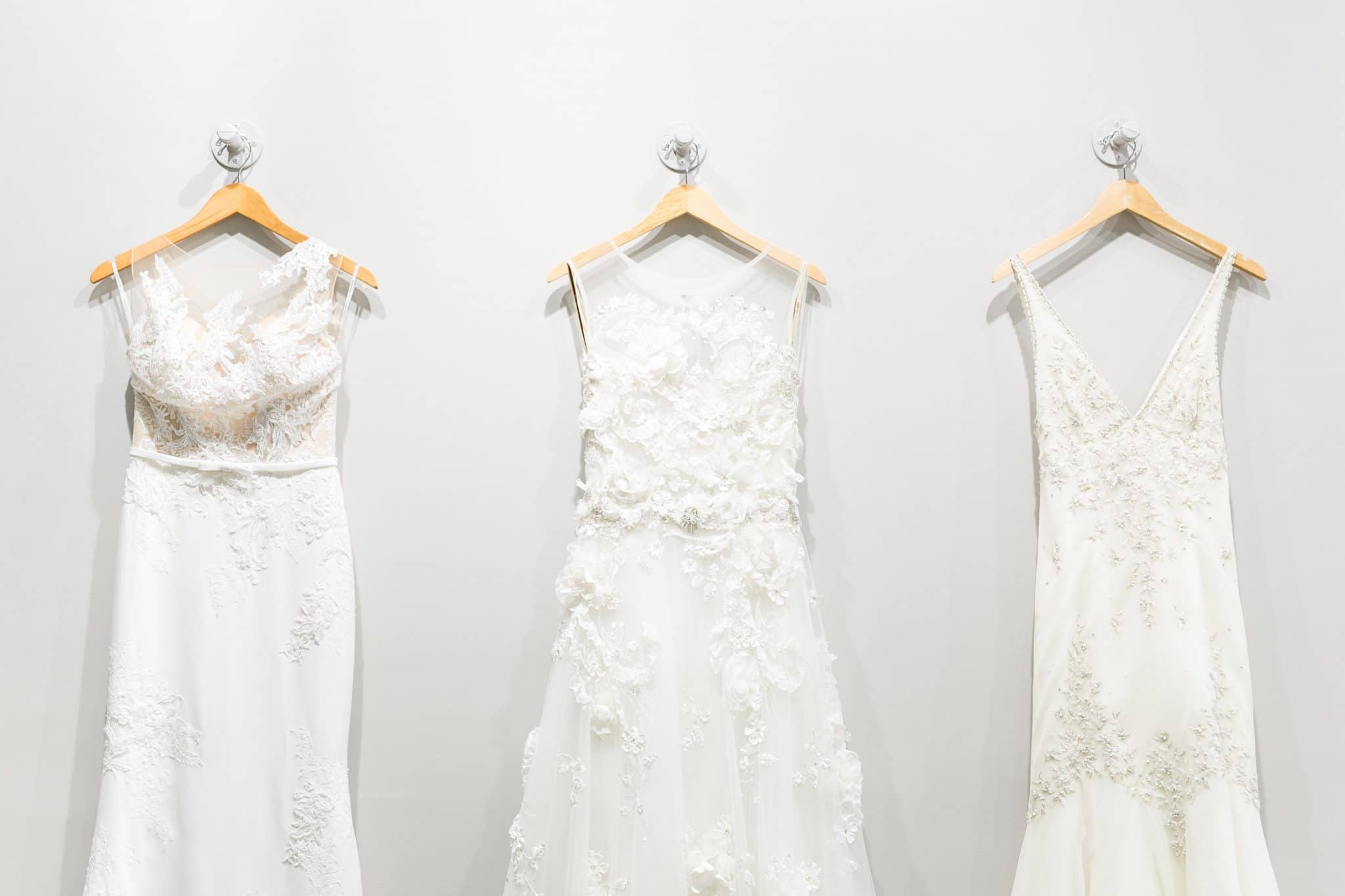 3 wedding dresses hanging on a white wall