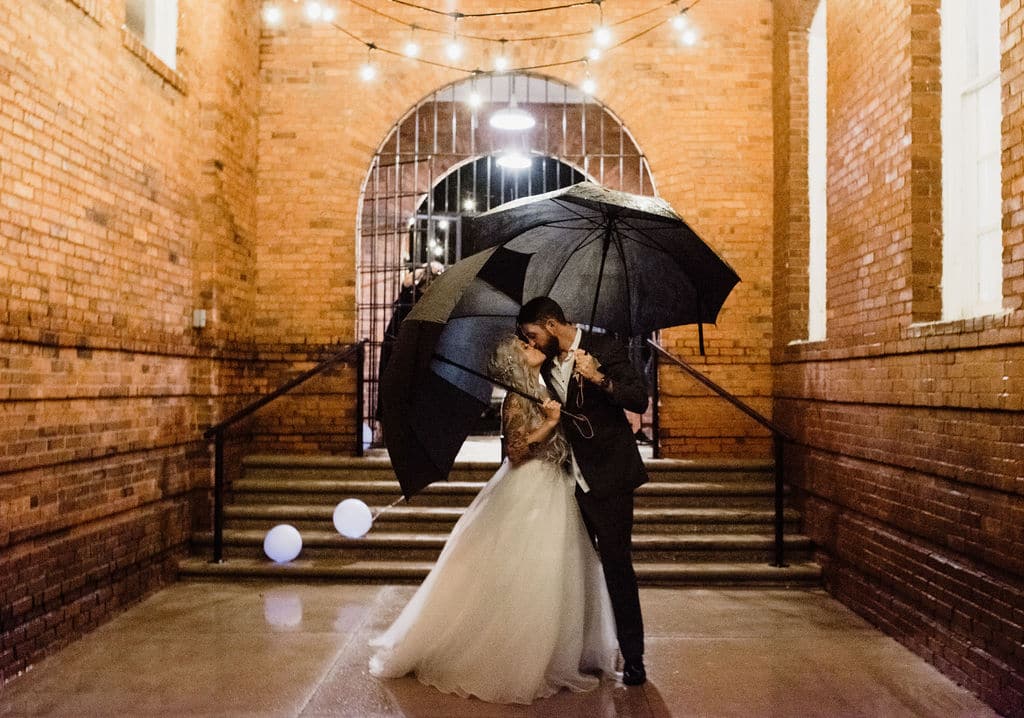 bride groom kissing outside under umbrellas