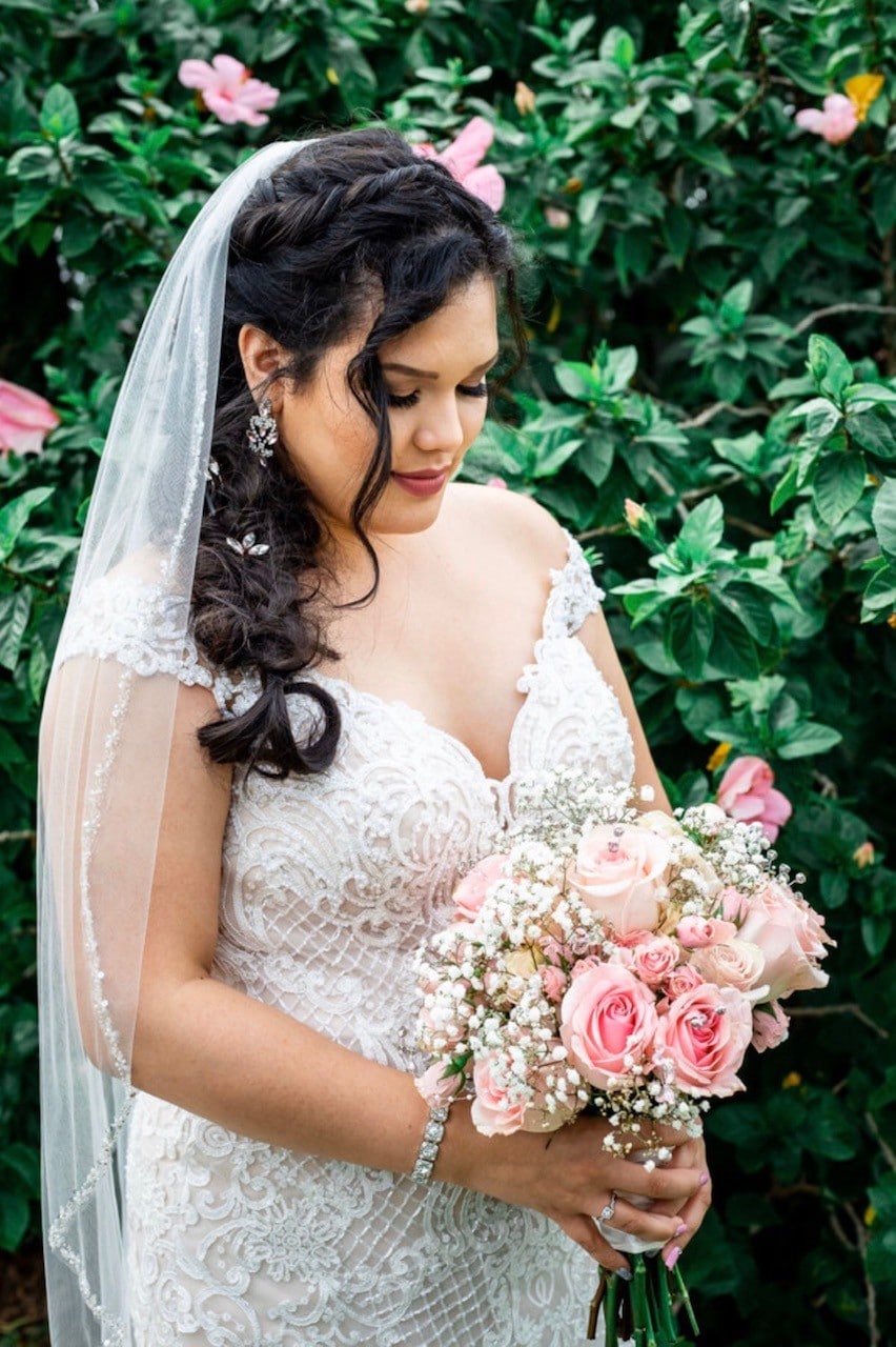 With This Ring, bride looking down at pink rose bouquet in gown and veil