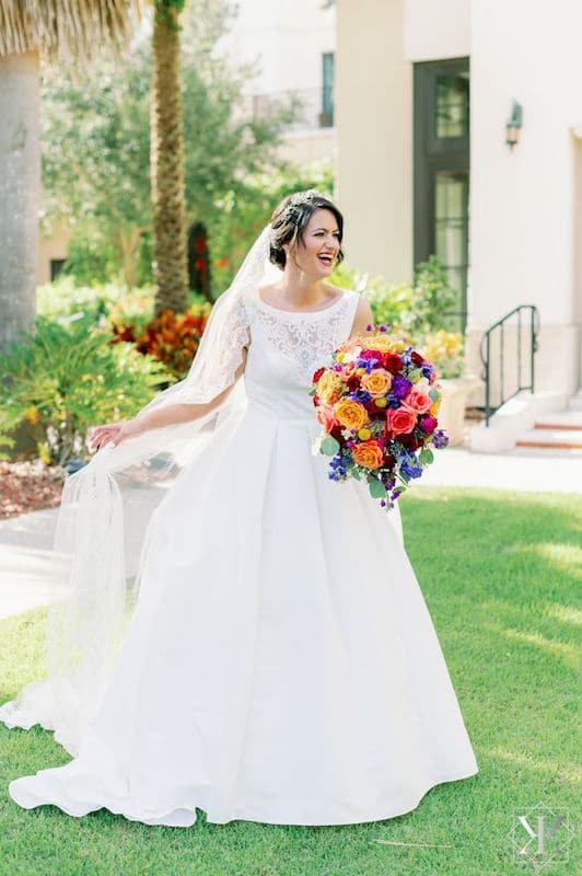Just Marry bride walking outside towards her wedding ceremony with a colorful bouquet of flowers