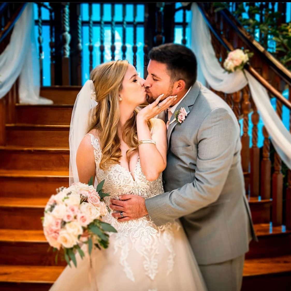 bride and groom kissing in front of staircase