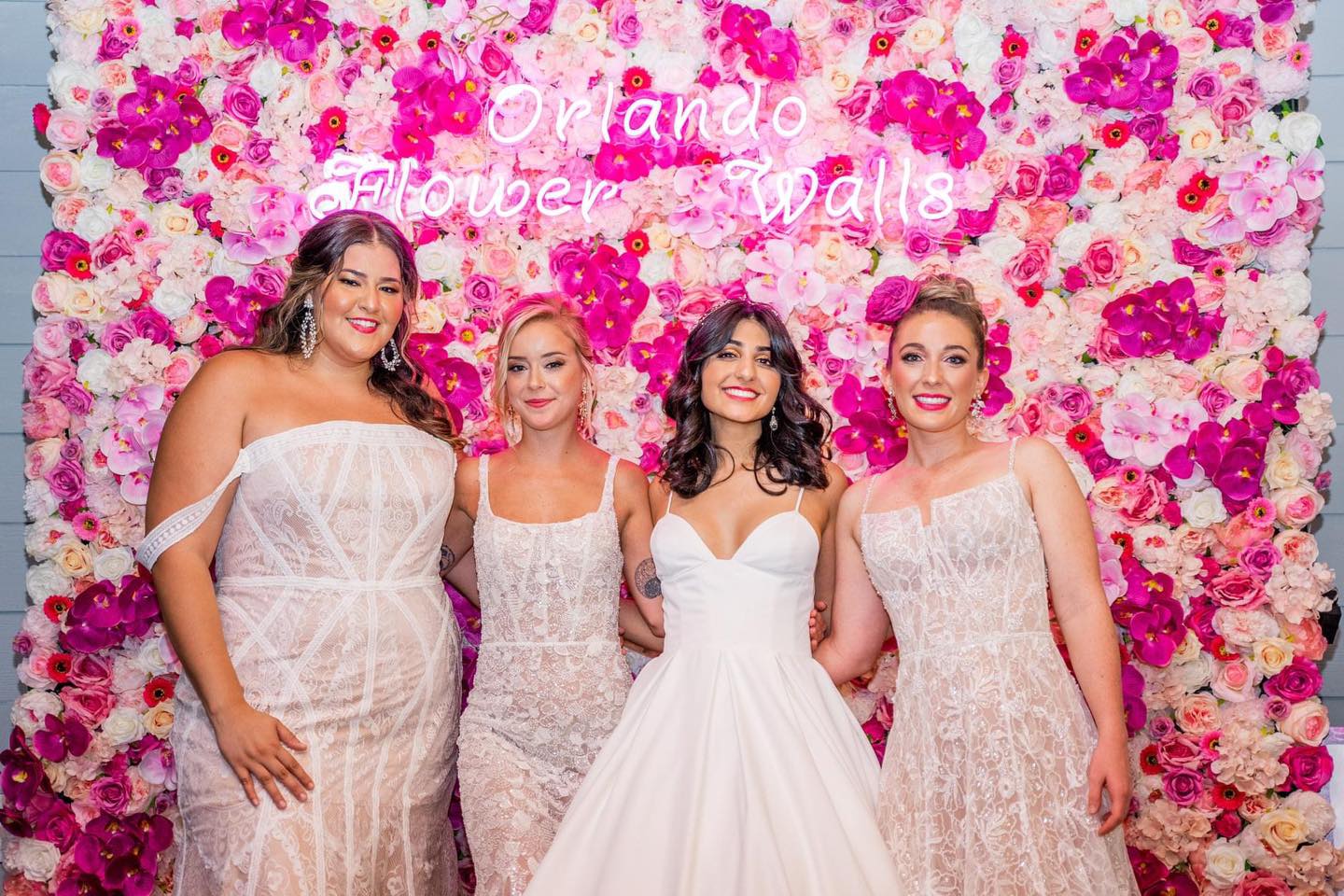 bride and bridesmaids in front of flower wall