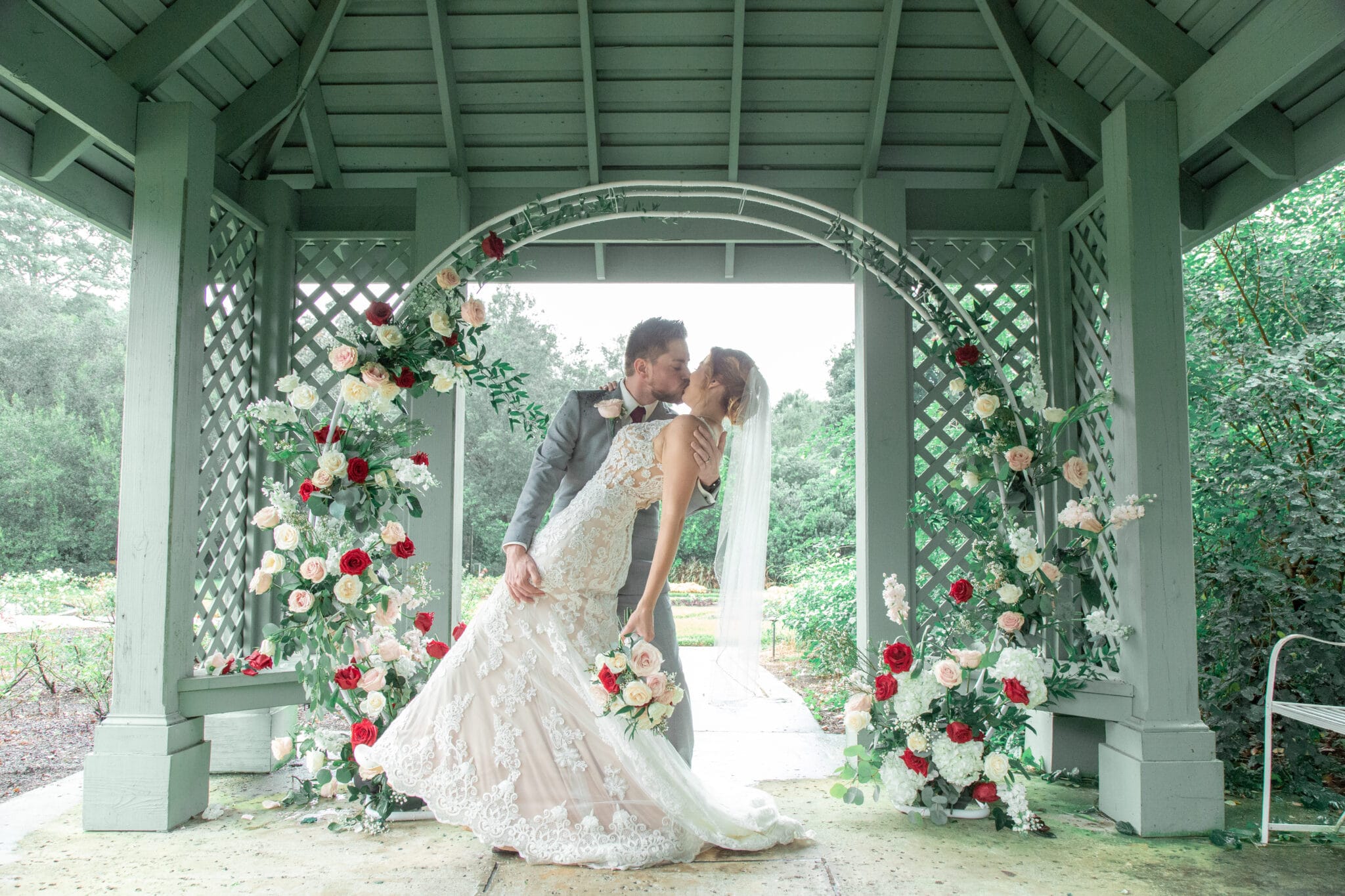bride and groom in front of ceremony arch with floral under a gazebo