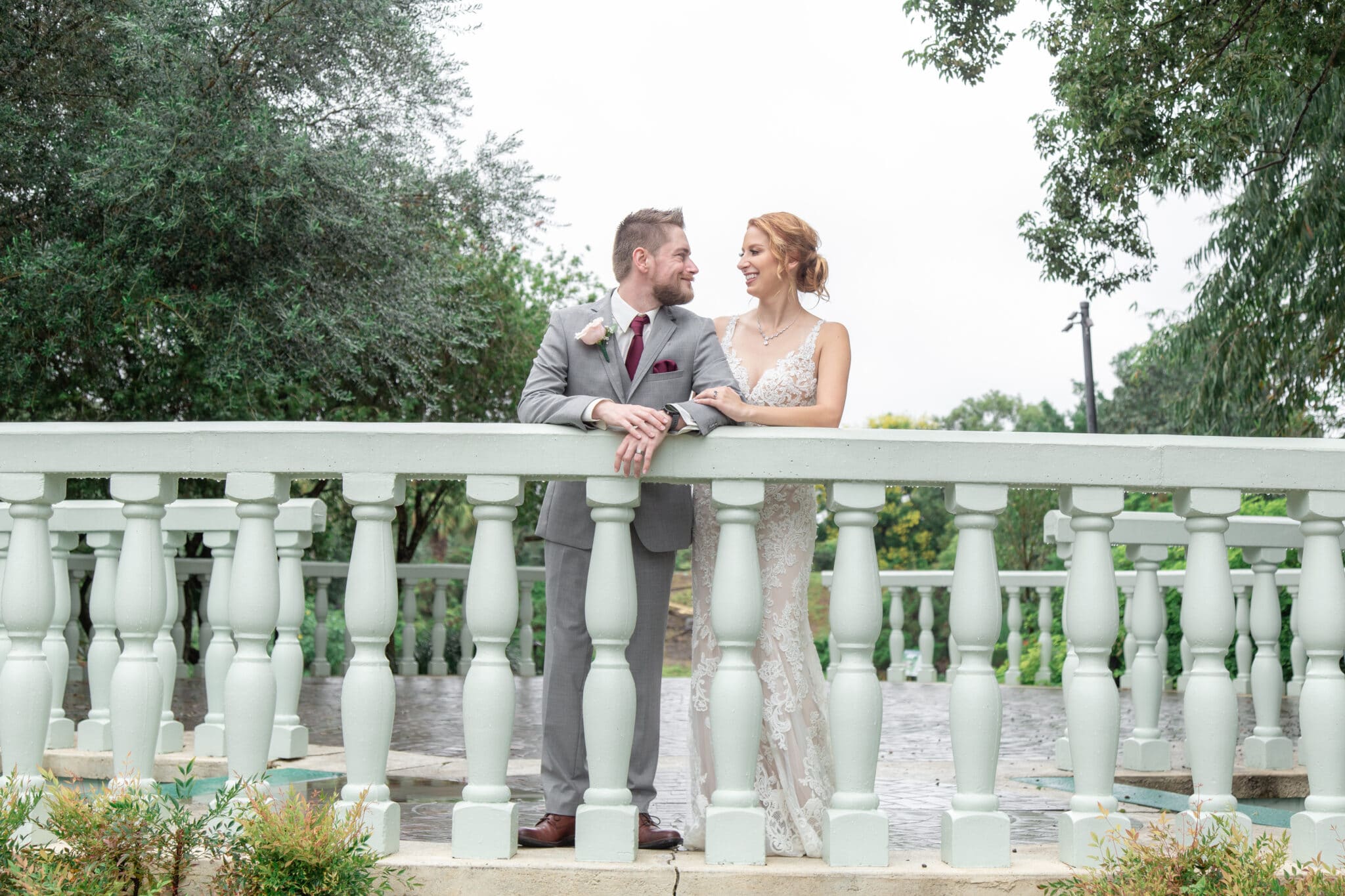 bride and groom in front of white railing looking at each other