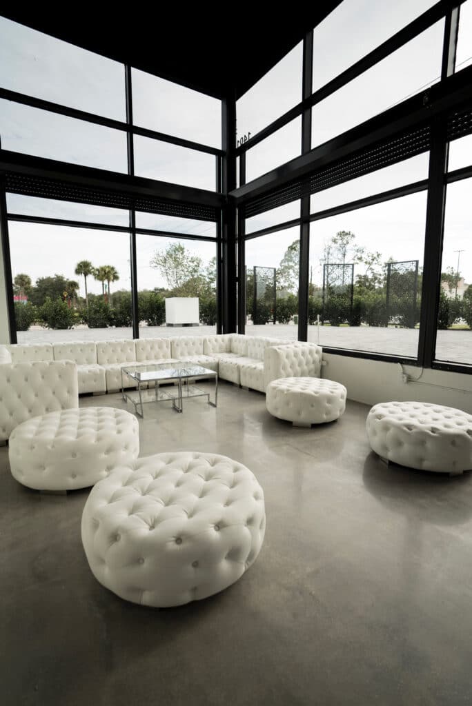 white couch and round white ottomans in modern room with walls of windows