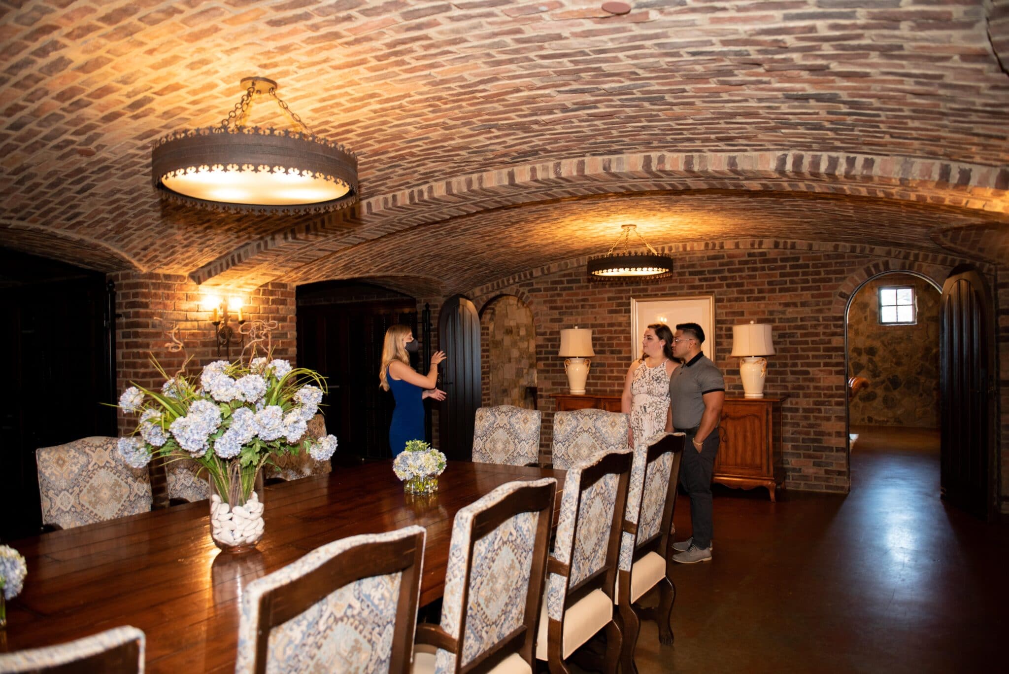 couple standing together in wine cellar of wedding venue listening to tour guide explain the venue to them