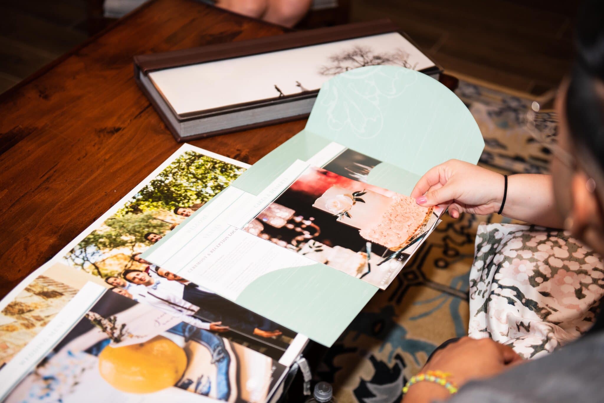 couple looking through catering and venue package information on top of wedding picture albums sitting on a coffee table