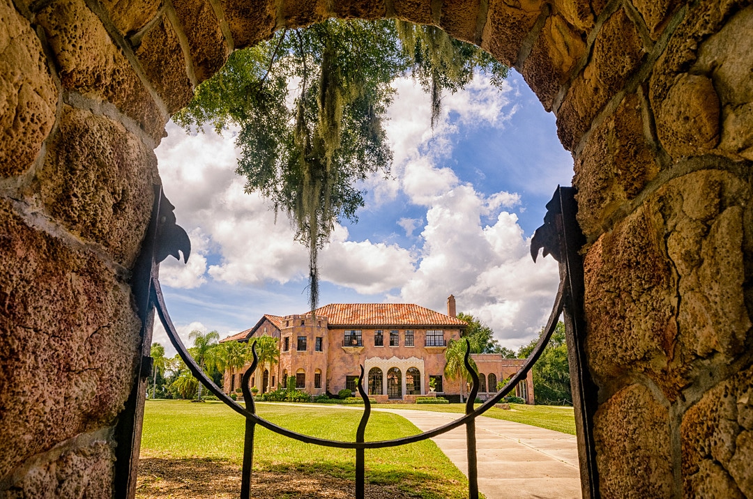 looking through brick arch over wrought iron gate at florida wedding venue the howey mansion