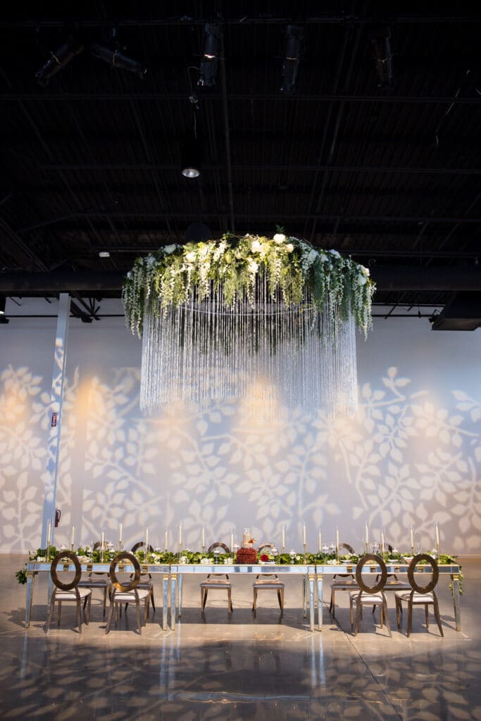 round floral chandelier hanging above long white table