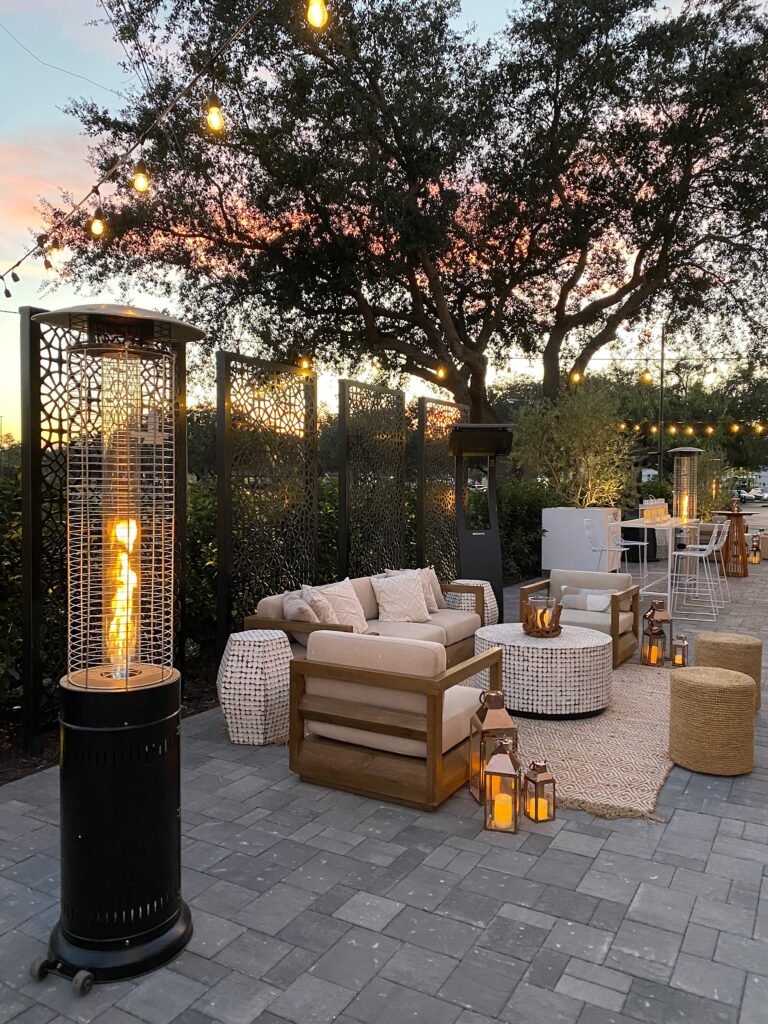 gray patio with brown outdoor furniture and space heater at sunset