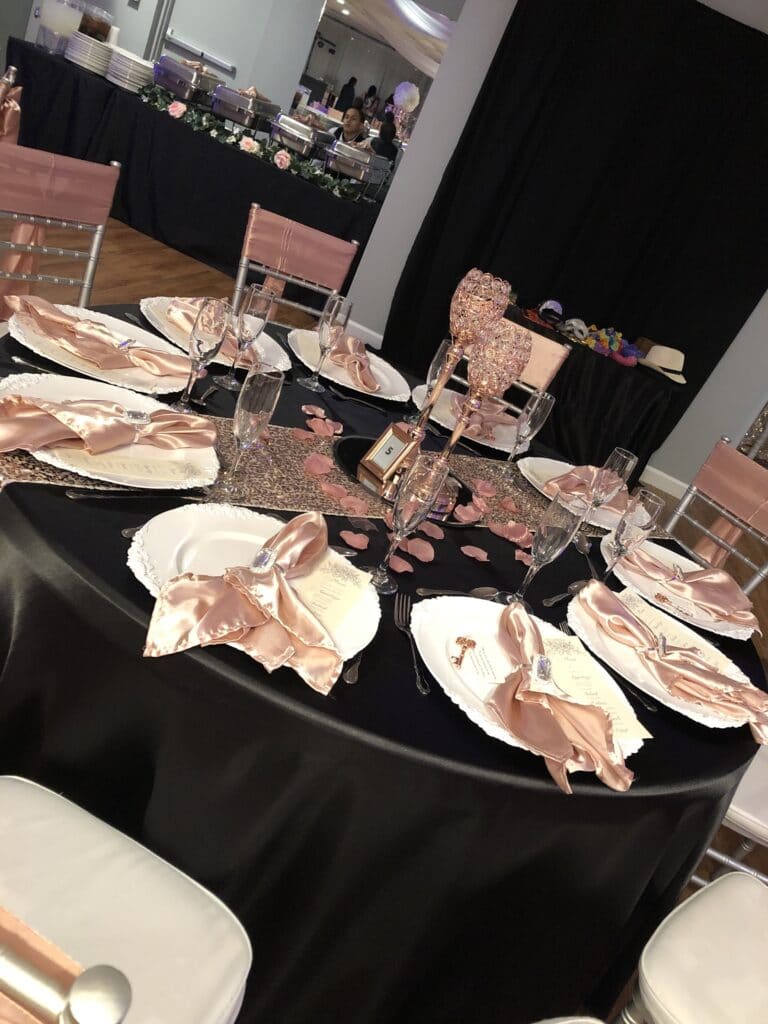 round table with black tablecloth white dishes and pink accents